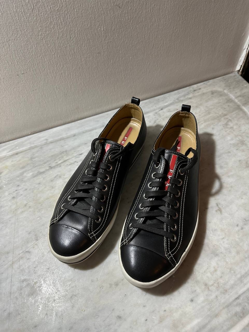 Prada Black Leather Low-Top Sneakers With White Sole And Red Tongue Accent